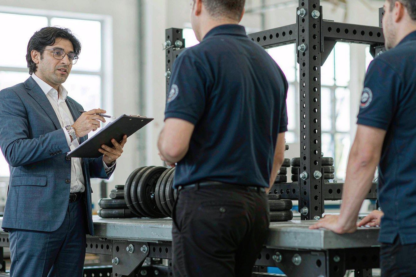 Auditor with a clipboard talking directly with assembly line workers